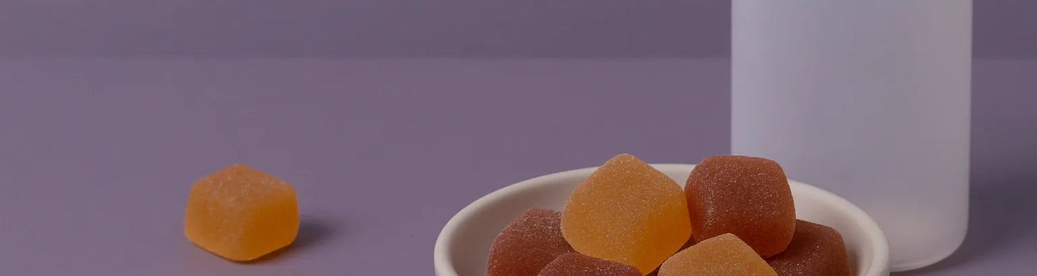 CBD- und CBN-Melatonin-Gummibärchen in einer Schale mit Flasche auf lila Hintergrund