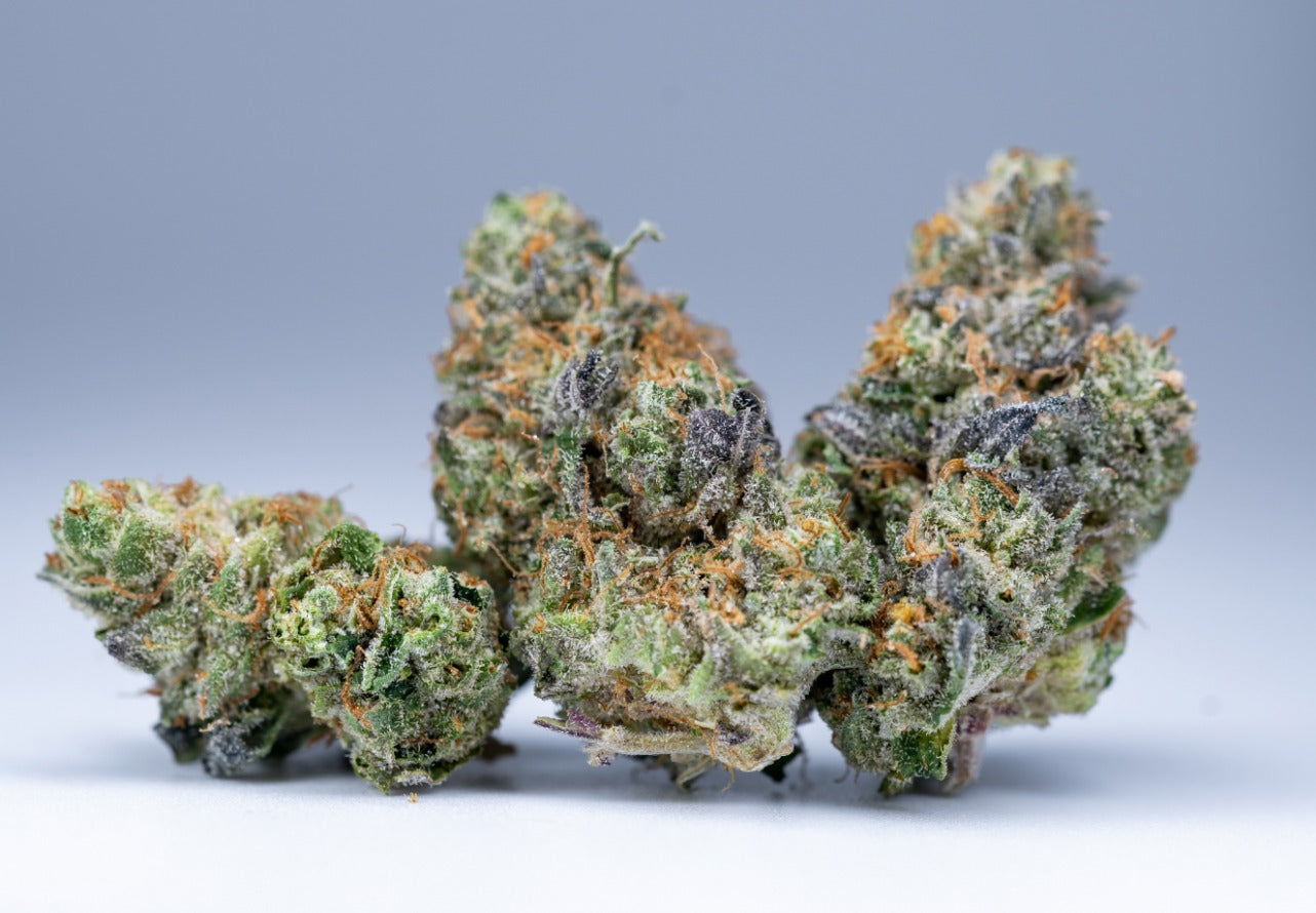 Cannabis flower buds with crystalline trichomes against a neutral background