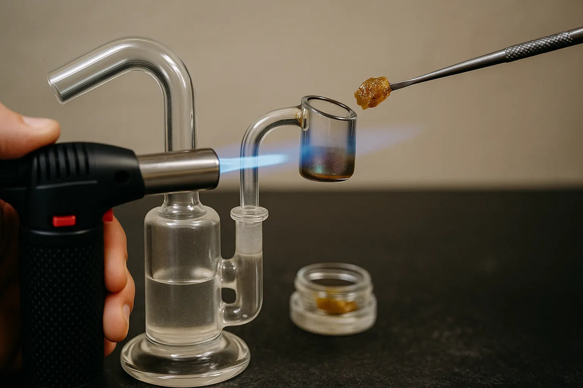 Eine Person benutzt ein Dab Rig, um Cannabis-Konzentrat zu inhalieren, Nahaufnahme in entspannter Wohnatmosphäre.